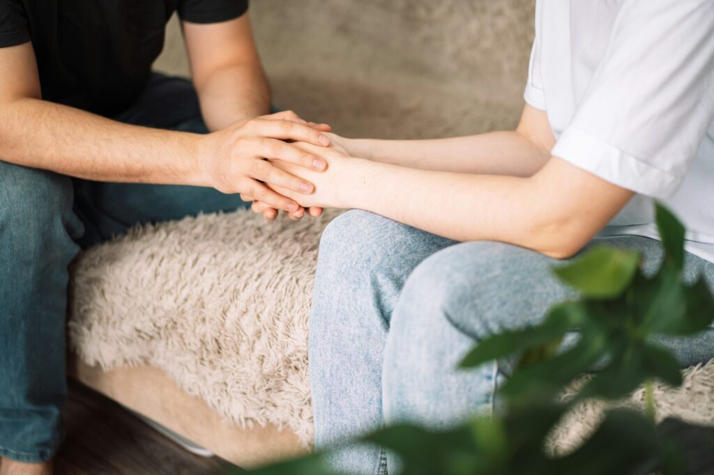 Man and lady hold each other's hands, support for loved one